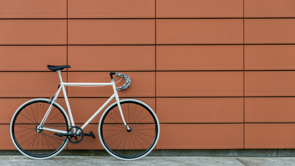 White fixie bike leaning on a red color wall