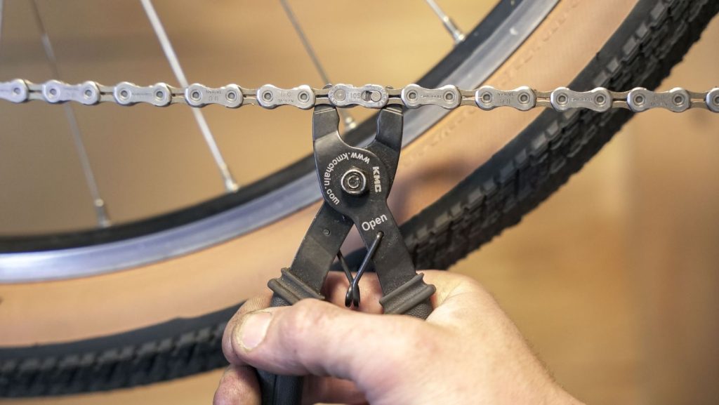 Man using a quick release tool to remove a bike chain