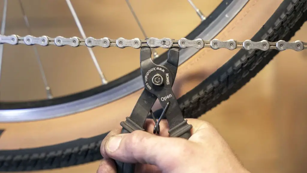Man using a quick release tool to break a bike chain