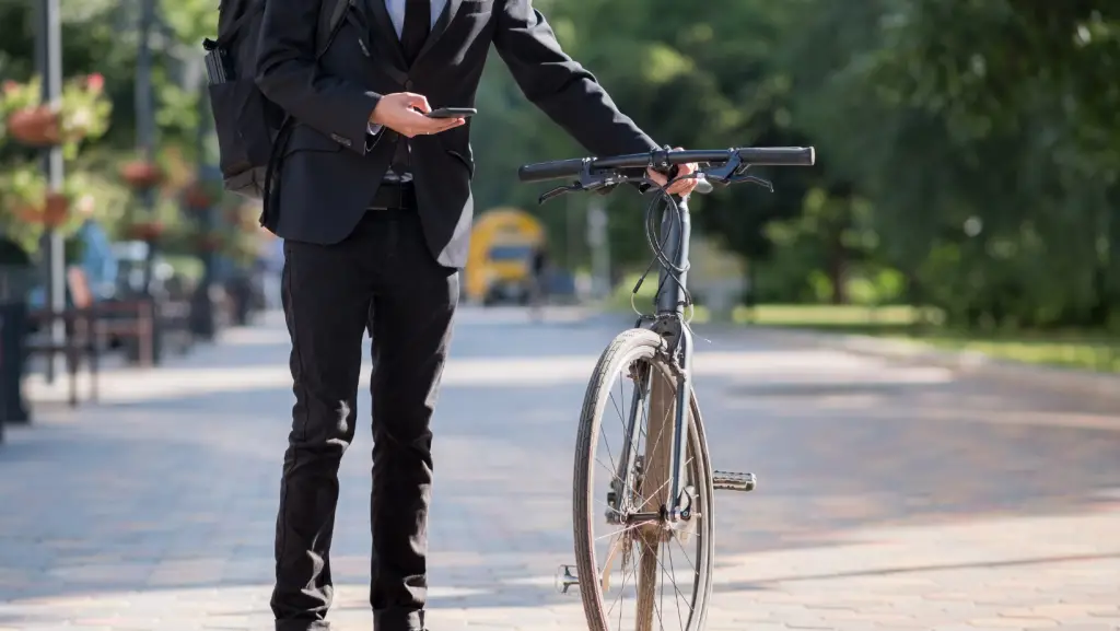 Suit dressed man checking his phone holding his bike with his left hand