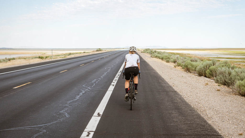 woman cycling on a flat road crossing a desert