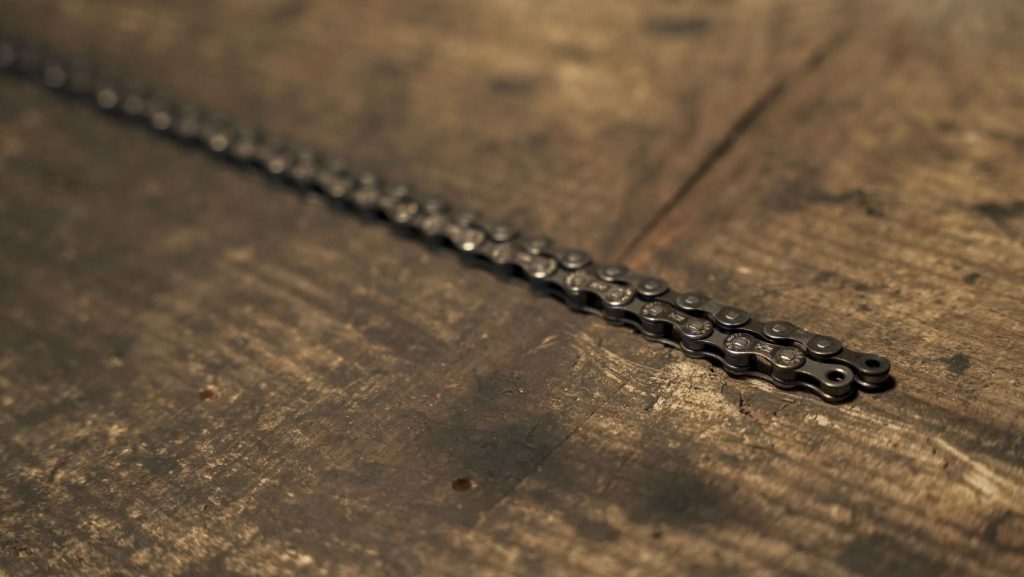 2 bicycle chains on a wooden table