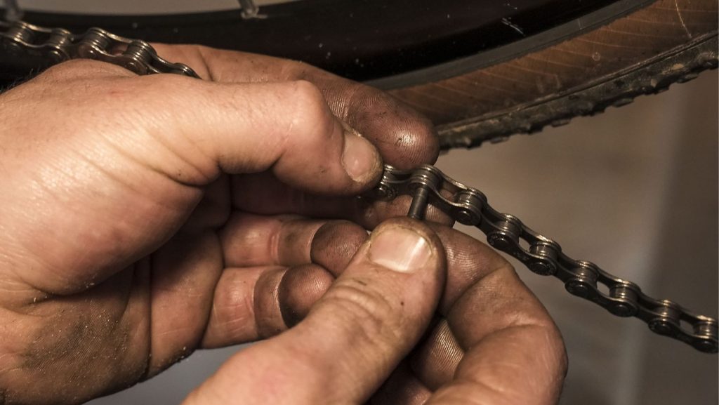 Man placing a new pin in a bike chain