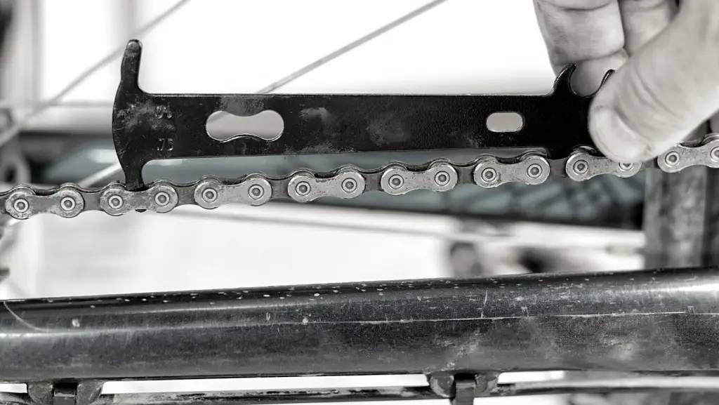 Close up view of a man's hand holding a bike chain wear indicator