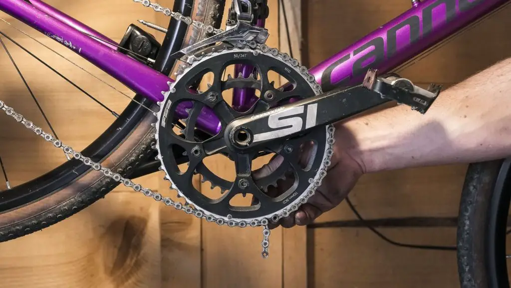 Hand of a man holding his bicycle chain on the large chainring