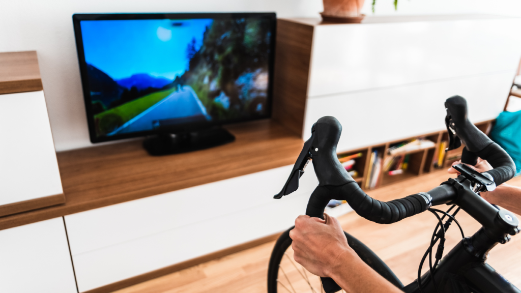Road bike handlebars in front of a TV while an indoor bike training session